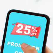 Promotions COS Systems Person holding phone in her hand. Display says 25% off, Promotion Code
